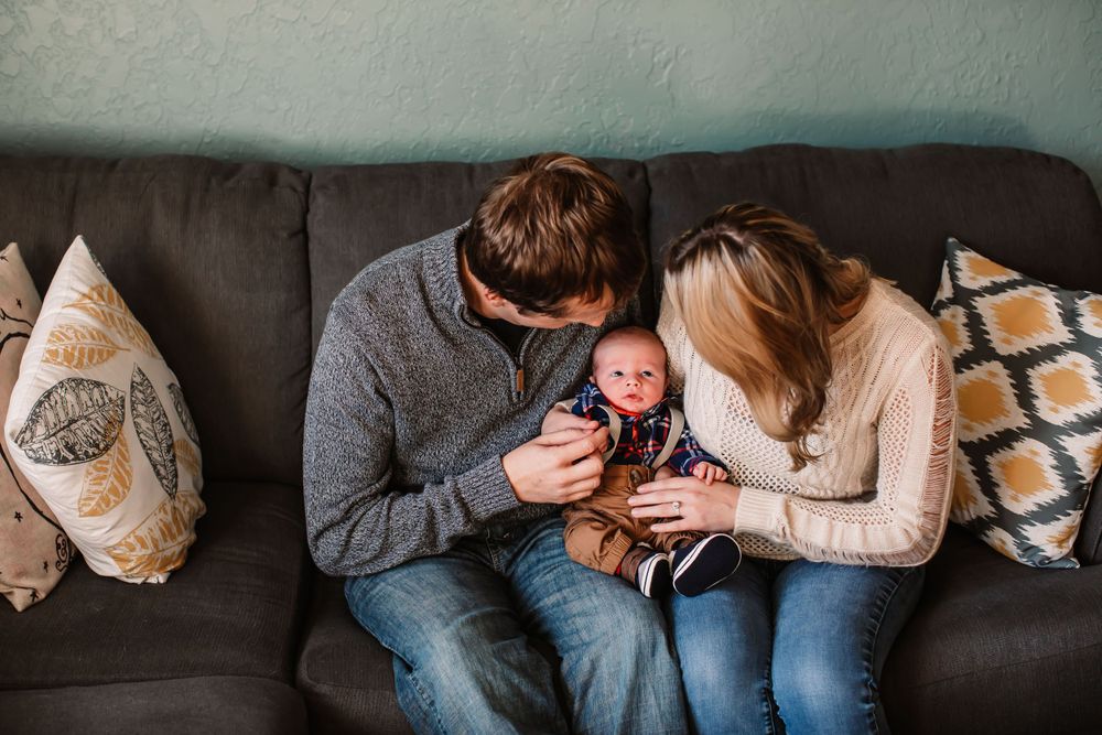 A heartwarming moment on a gray couch with a baby and cozy decorative pillows.