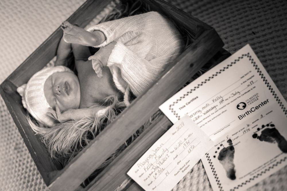 Black and white vintage photo of newborn with birth certificate.