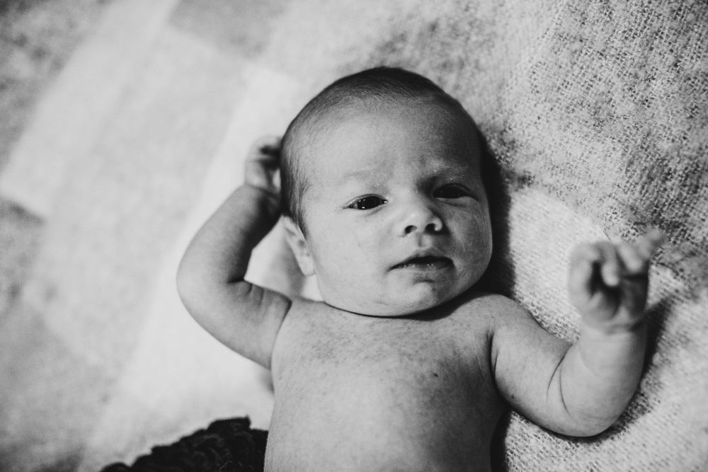 Black and white portrait of a newborn baby lying on soft fabric.