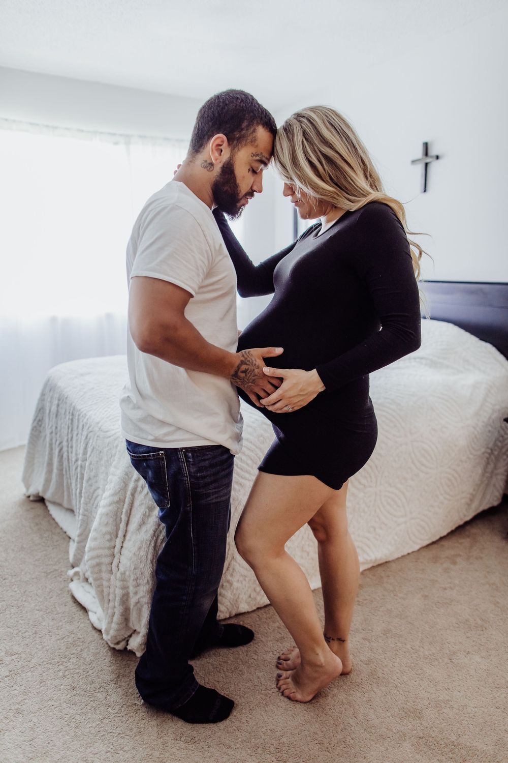Intimate maternity photo of couple in bedroom sharing tender moment.