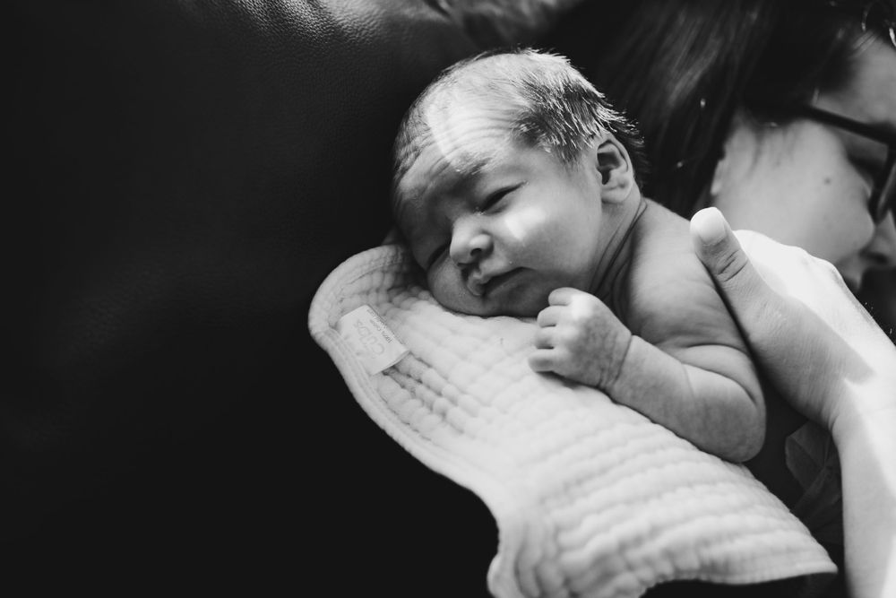 Black and white portrait of a peaceful newborn baby resting on soft fabric.