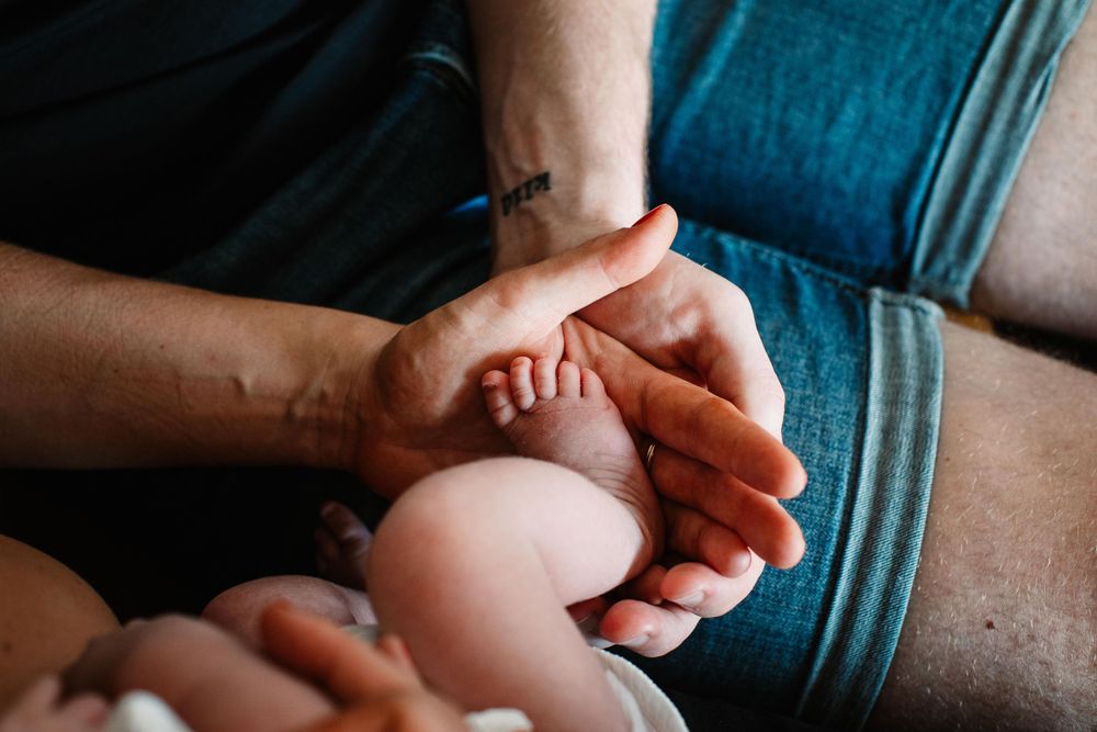 Close-up shot of tiny baby feet being held by adult hands.