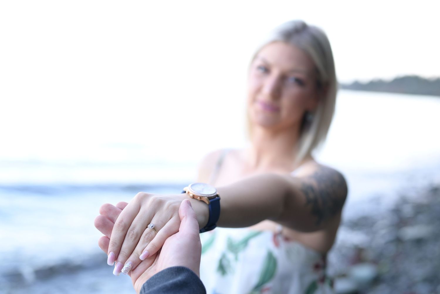 Photoshoot with outstretched hand in focus with women's face out of focus.
