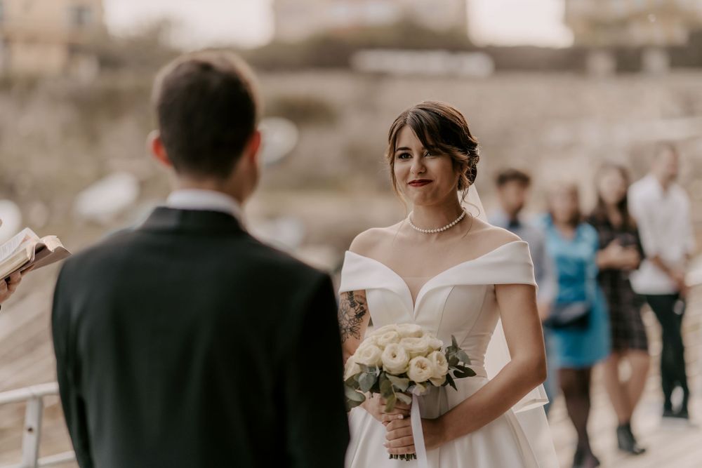 Intimate outdoor wedding ceremony with couple exchanging vows in front of guests and officiant.