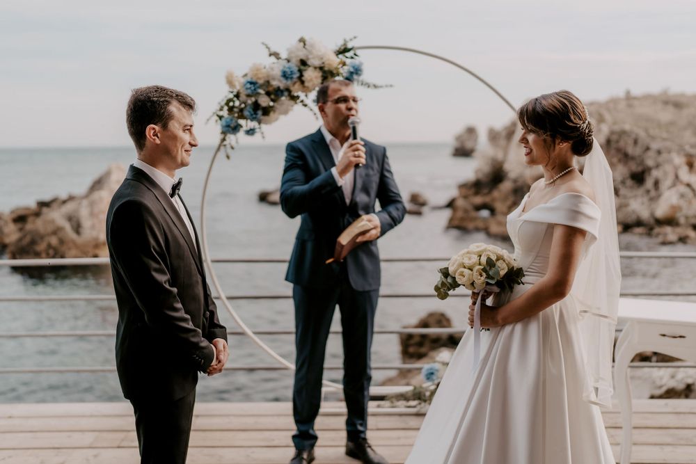 Wedding ceremony on a scenic waterfront deck with guests watching the couple's special moment.