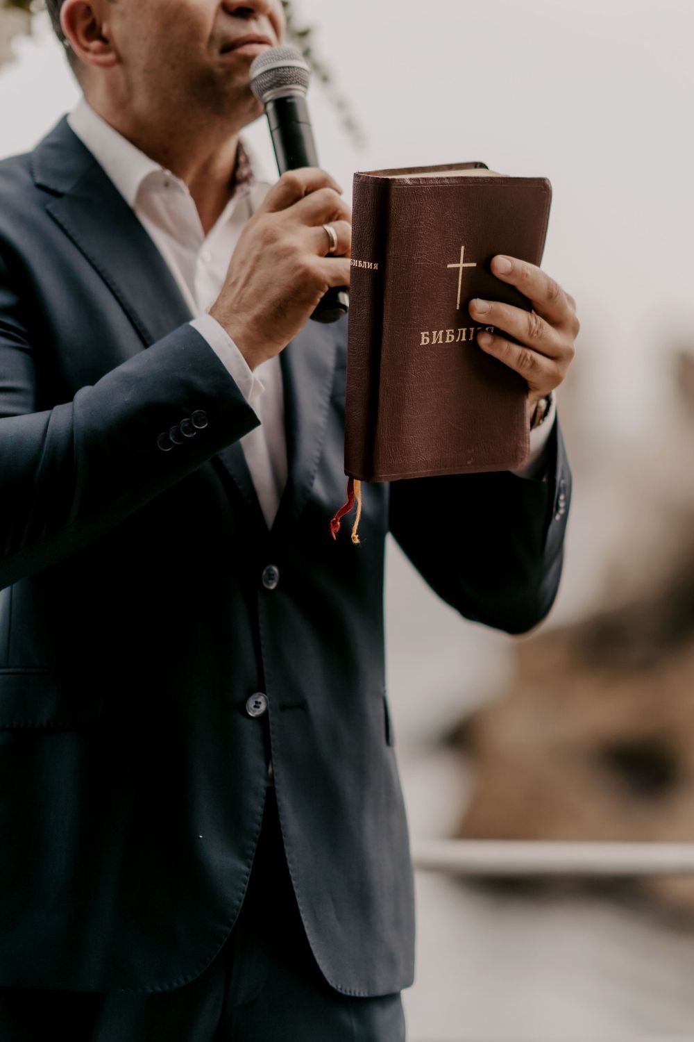 Close-up of officiant holding leather-bound ceremony book during wedding service.