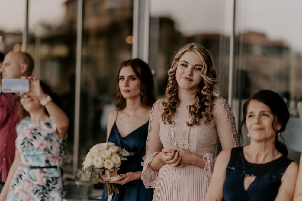 Wedding party members in pastel and navy dresses stand together during an outdoor celebration.
