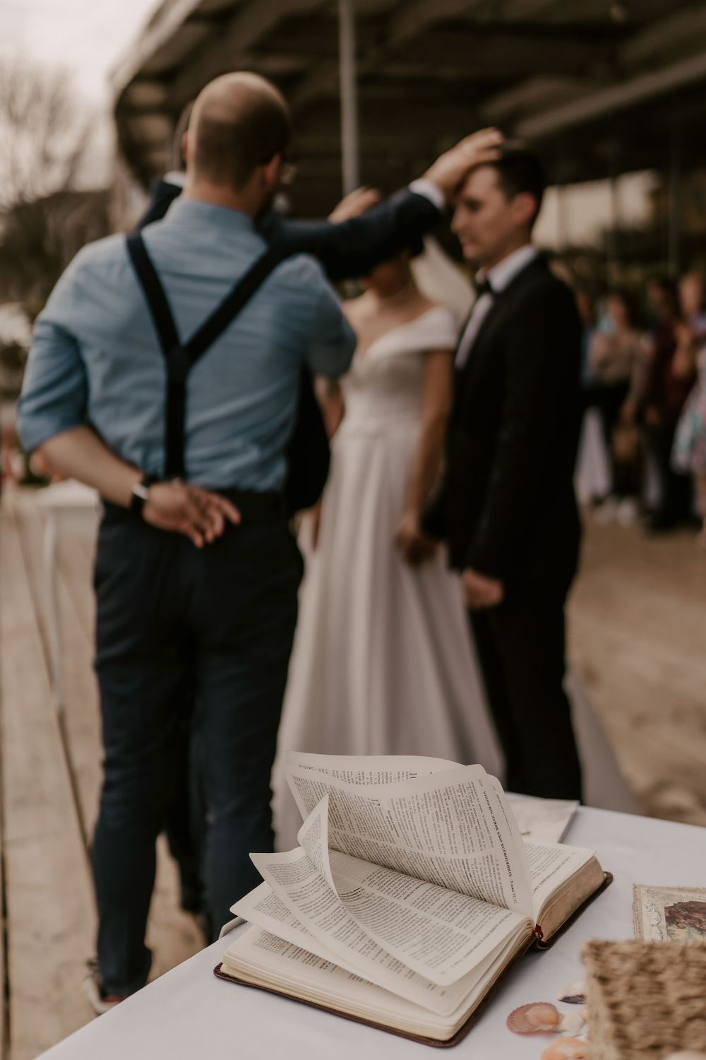 An open book rests on a table during a wedding ceremony with people standing in the background.