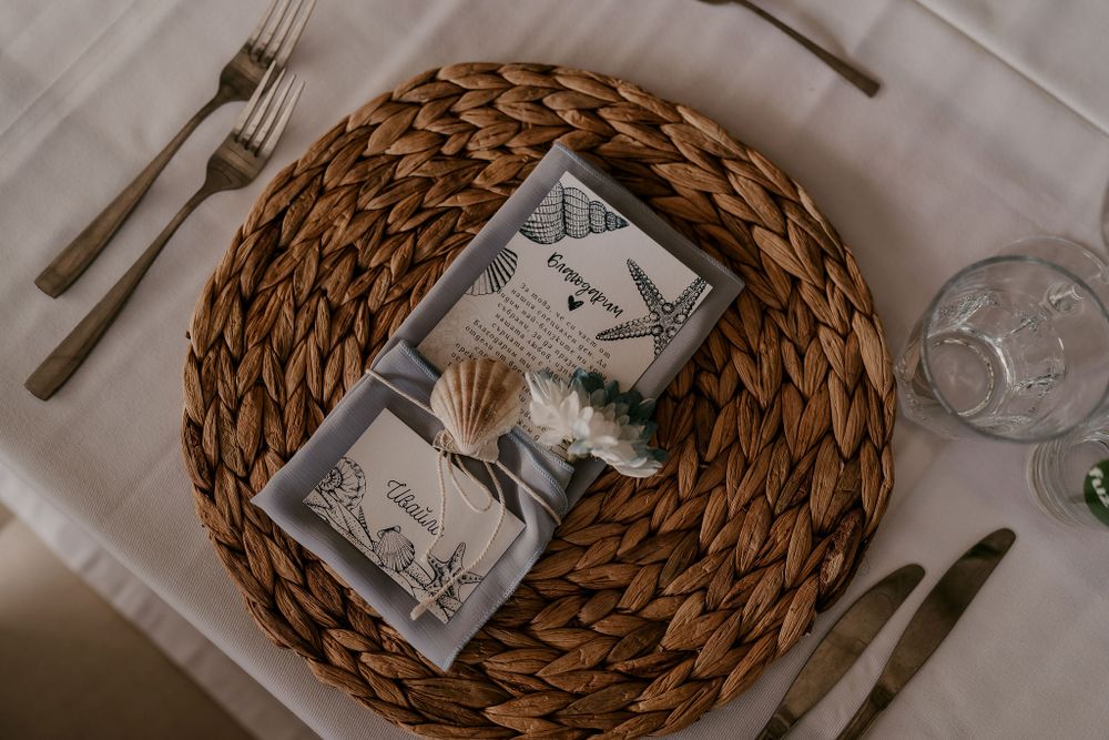 Wedding place settings feature woven charger plates and minimalist table decorations.