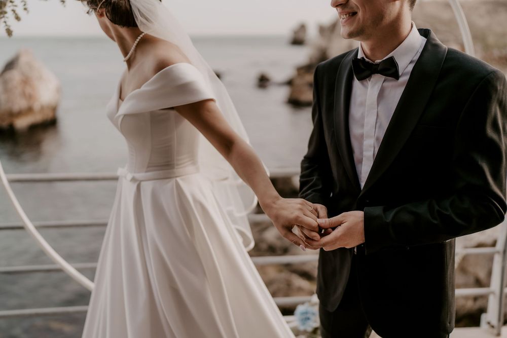 Intimate wedding ceremony on wooden deck overlooking rocky coastline.