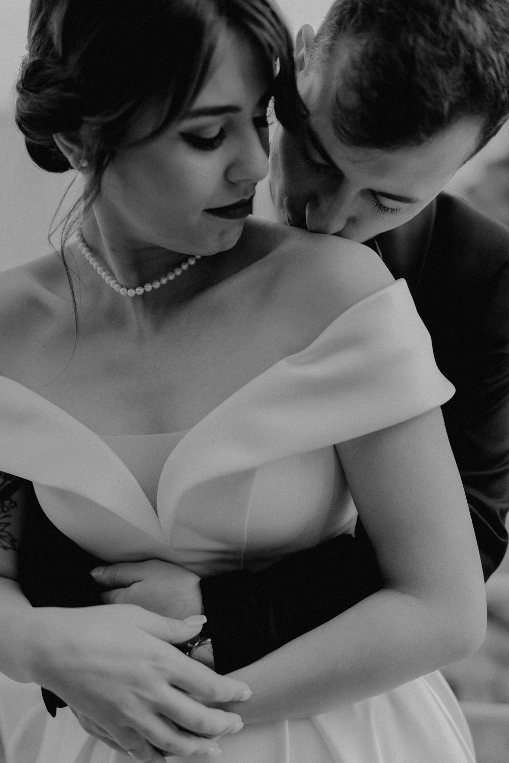 Black and white intimate portrait of couple in wedding attire sharing romantic moment.