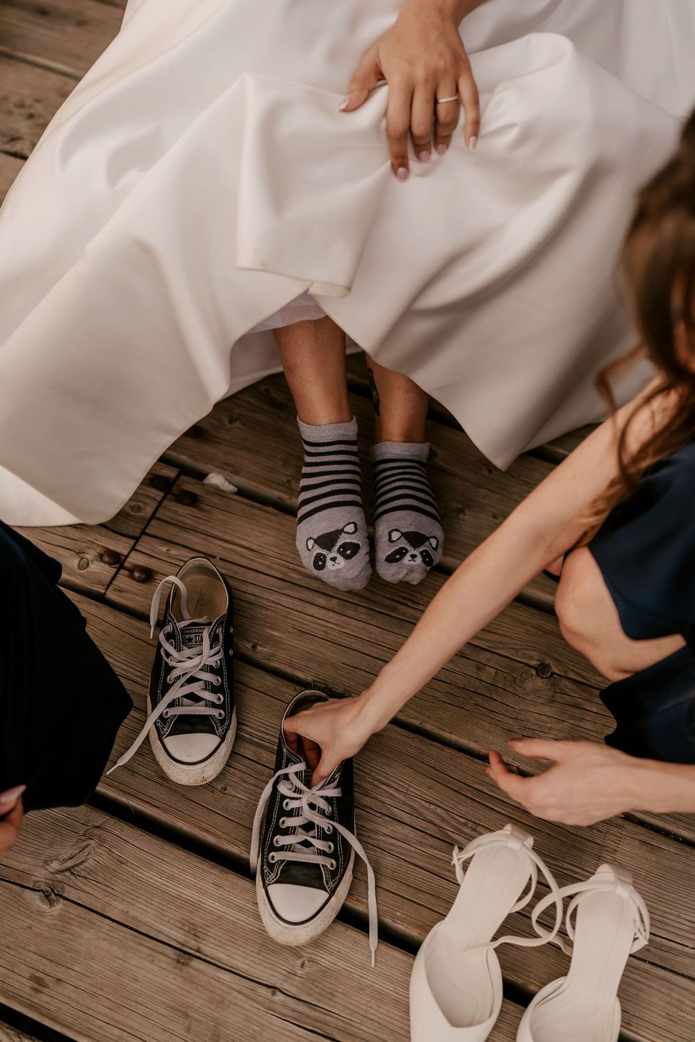 Wedding shoes and socks arranged on wooden deck boards during seaside celebration.