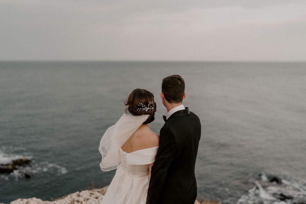 A couple shares an intimate moment overlooking rocky coastal waters.
