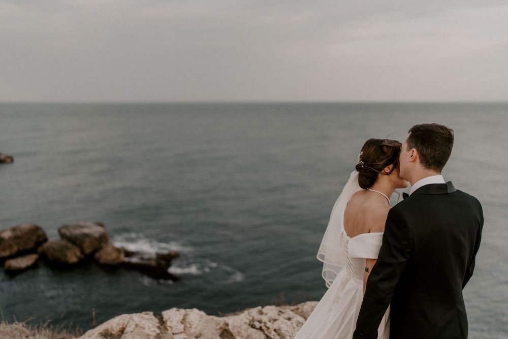 A couple shares a romantic moment on coastal cliffs overlooking the ocean.
