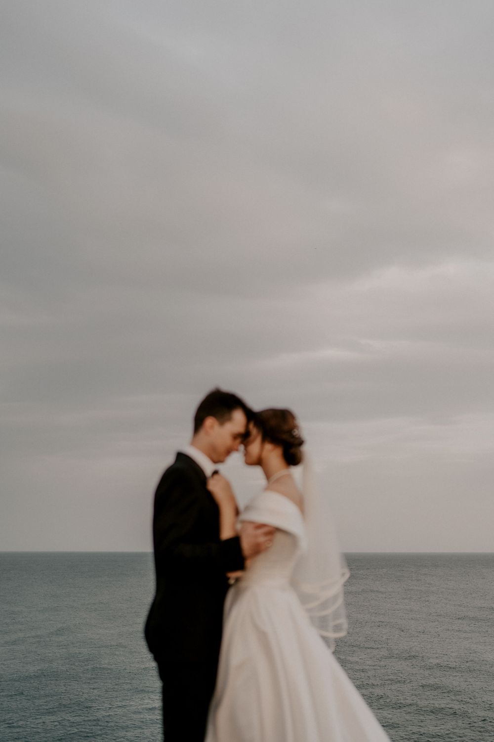 A tender wedding moment captured against a misty ocean horizon.
