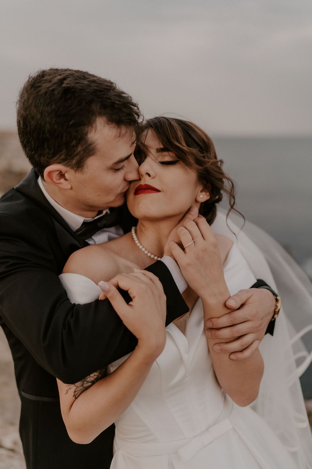 Romantic close-up of newlyweds sharing an intimate moment against the sea.