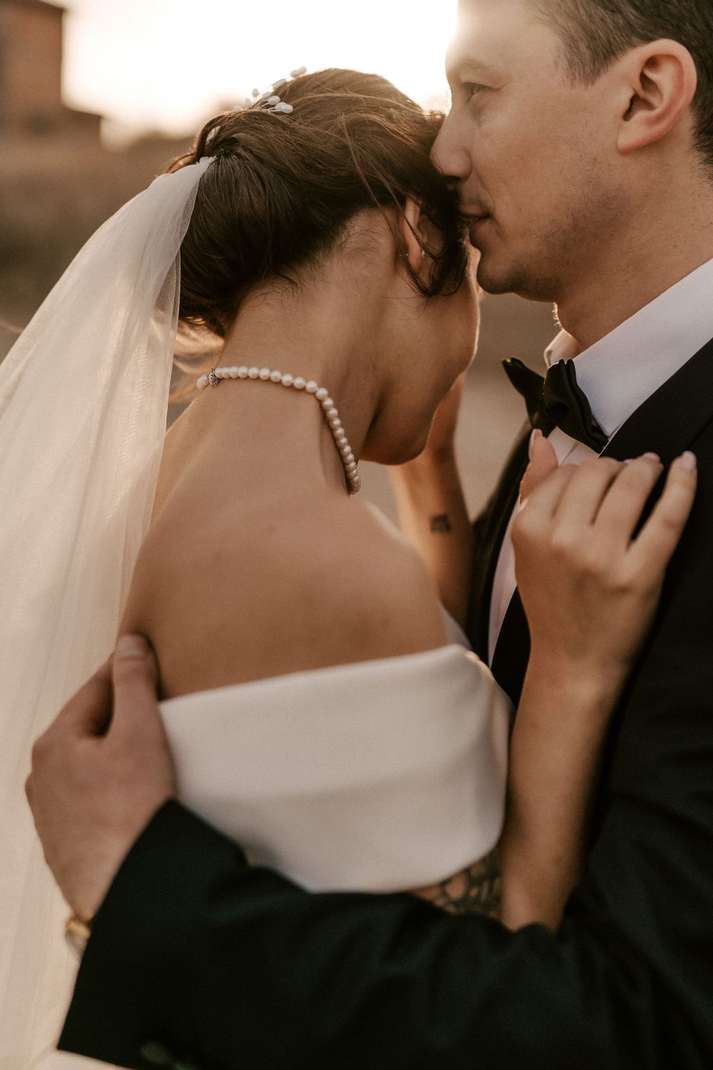 Close-up of a romantic wedding moment with pearl necklace details and elegant attire.