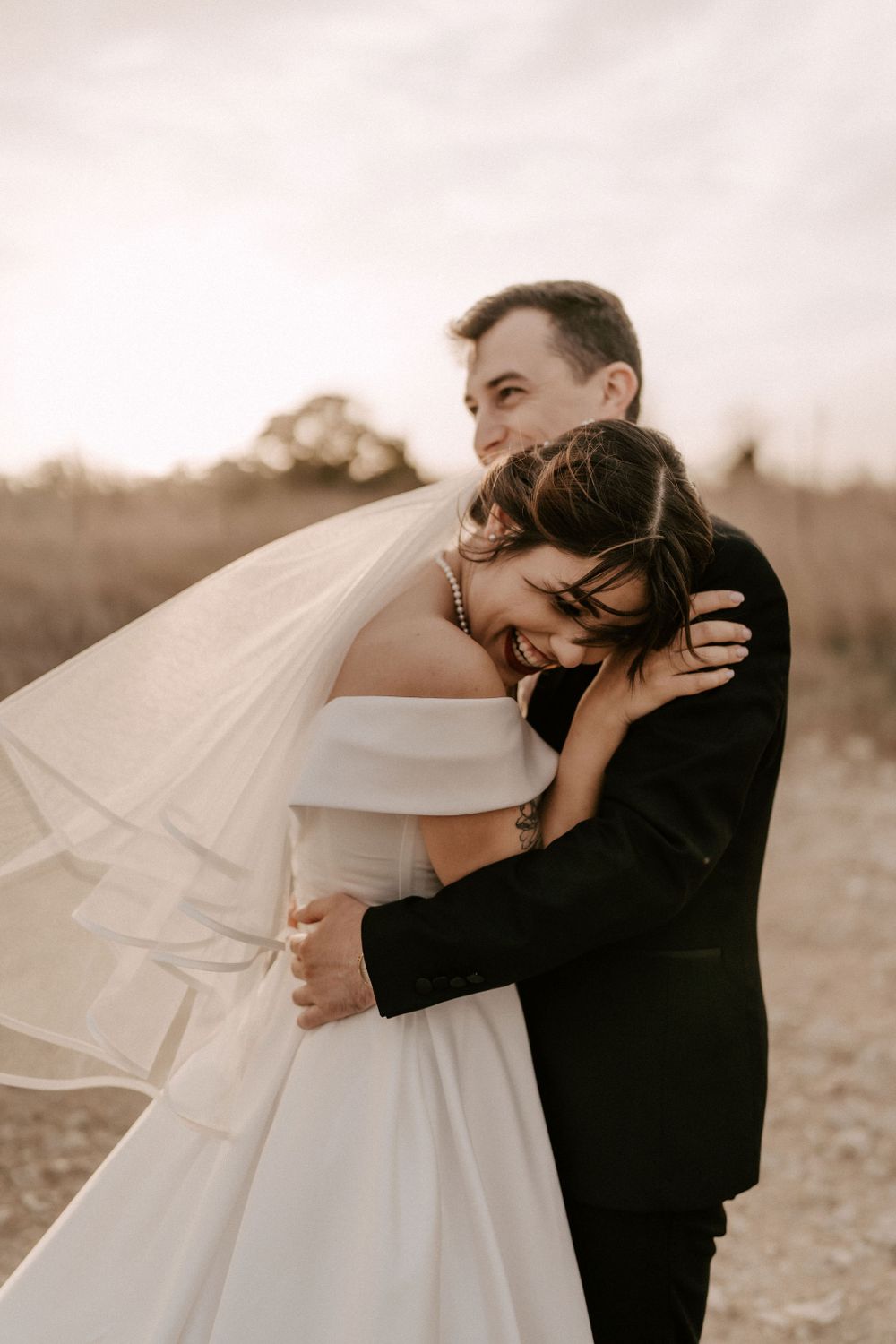 Joyful wedding couple shares playful moments in golden sunset light.