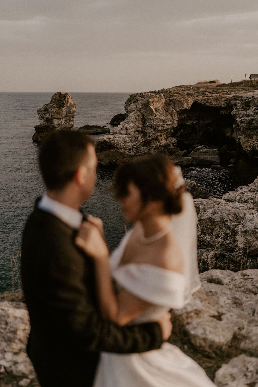 Romantic seaside moment with dramatic rocky coastline in background.