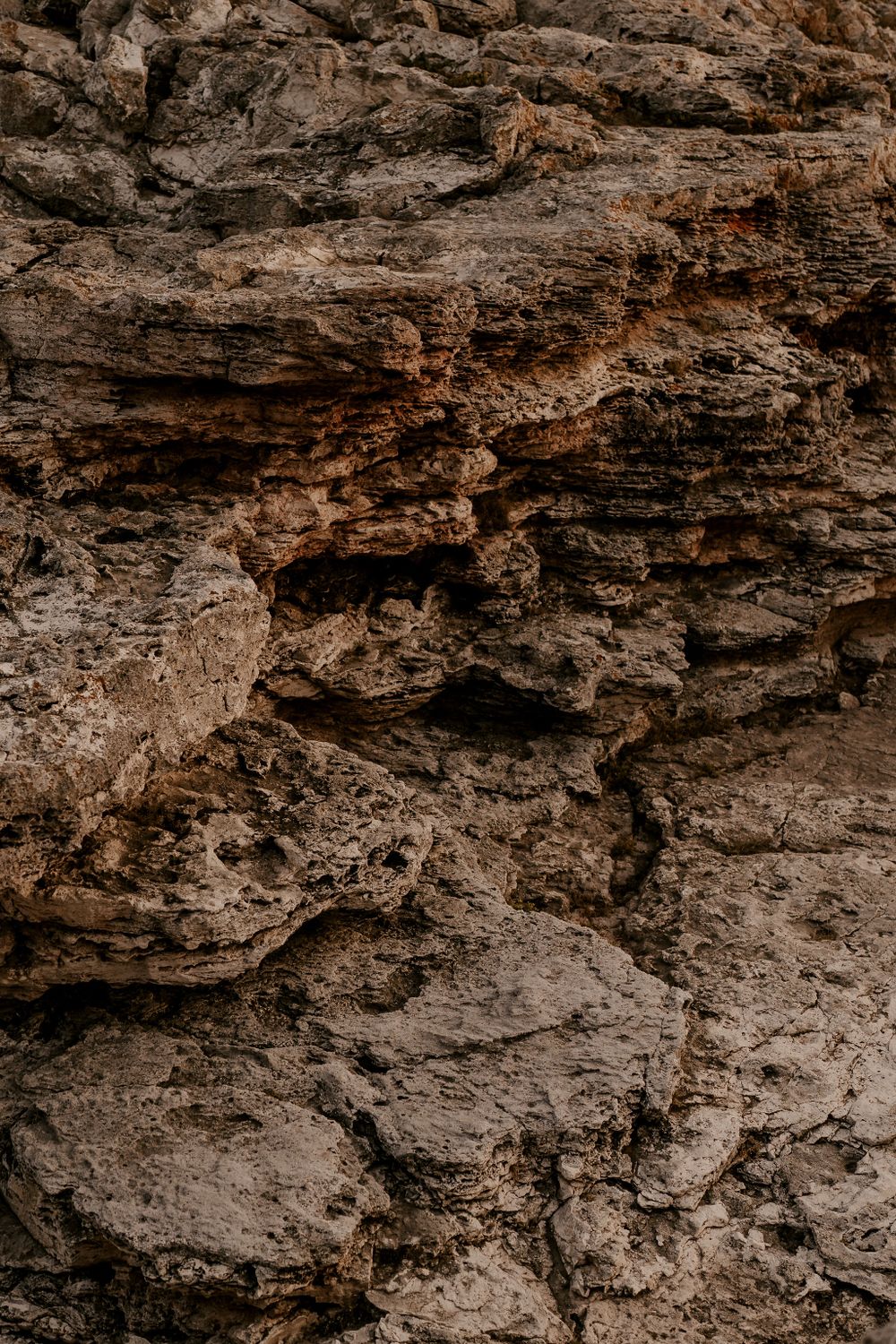 Dramatic rocky cliffs with textured limestone formations along a rugged coastline.