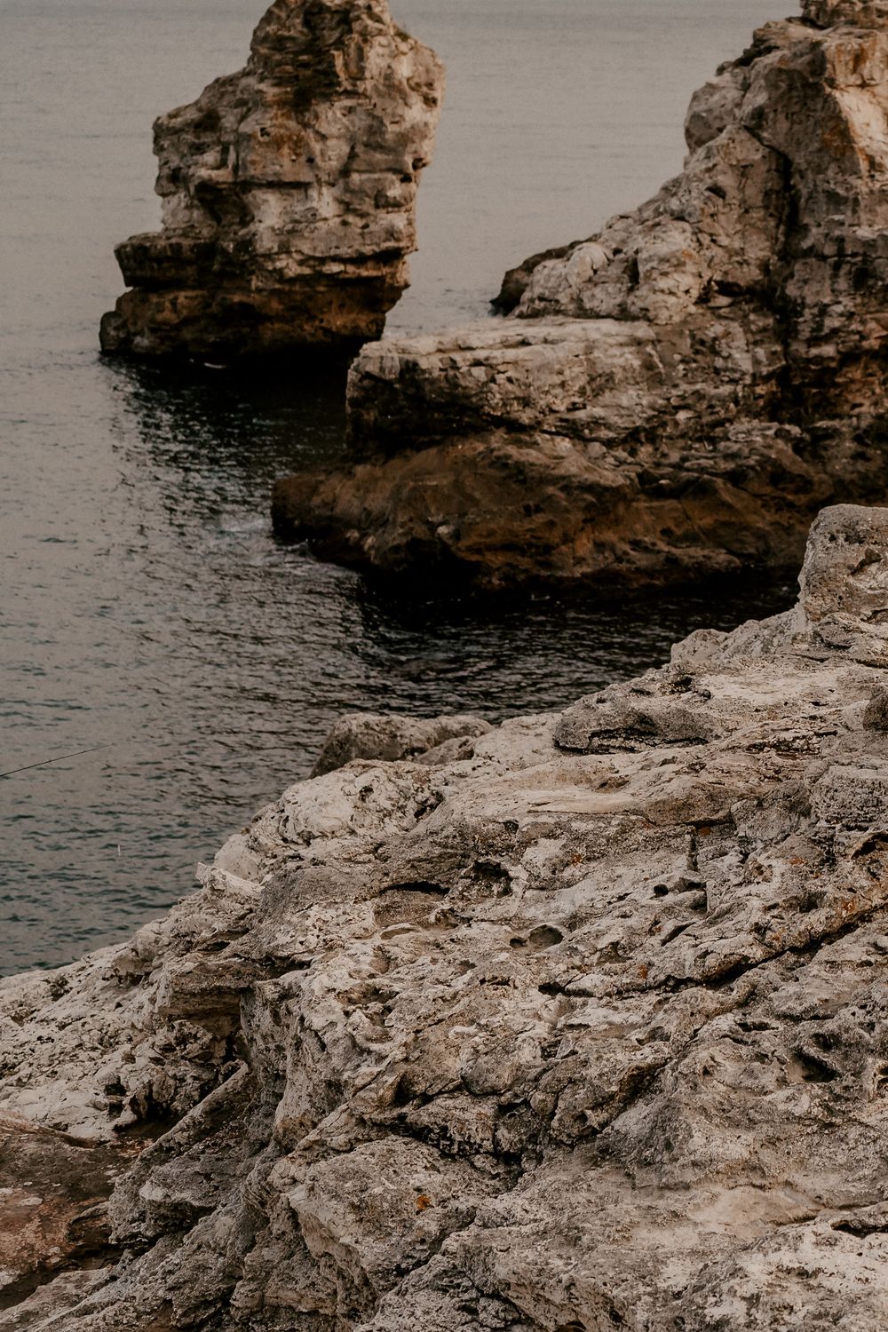 Jagged limestone formations and rocky outcrops extend into calm ocean waters.