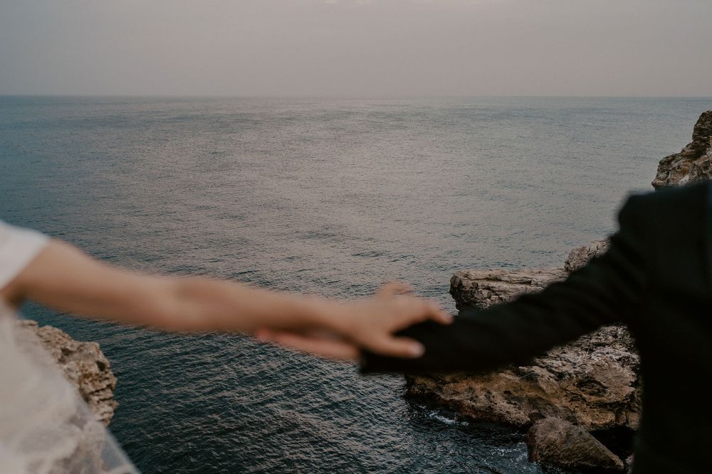 Rugged coastline with waves crashing against limestone cliffs during sunset.