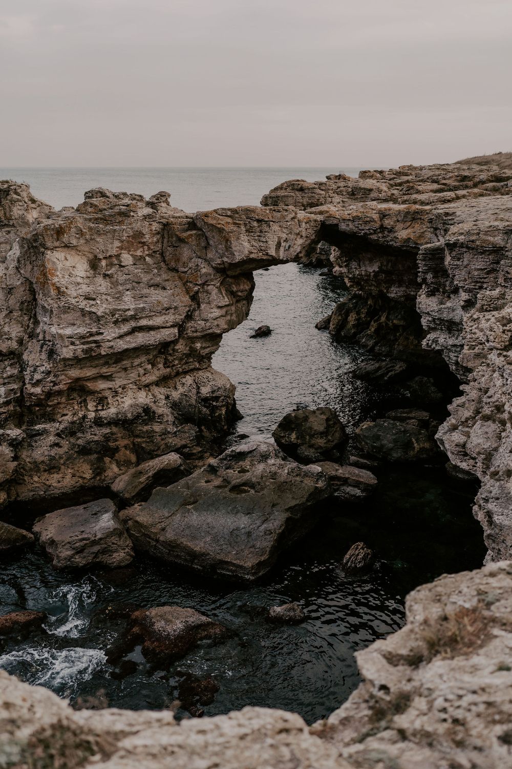 Dramatic rocky coastal cliffs overlooking dark ocean waters with natural stone formations and caves.