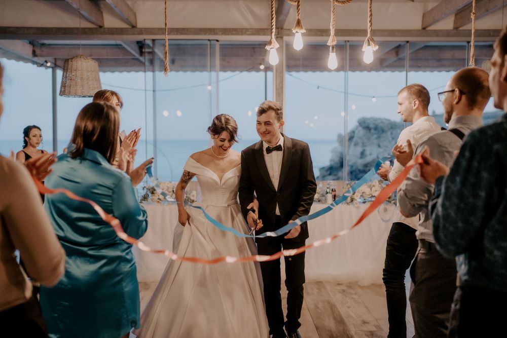 Wedding party gathered in a modern reception space with floor-to-ceiling windows.