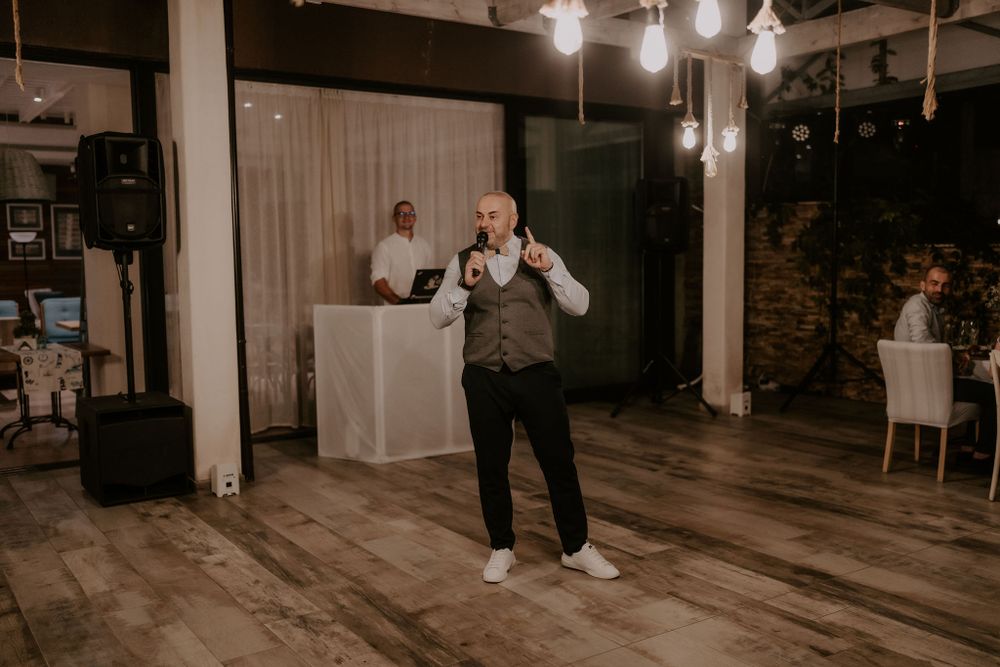 Newlyweds dance together in a modern venue with exposed ceiling and pendant lighting.