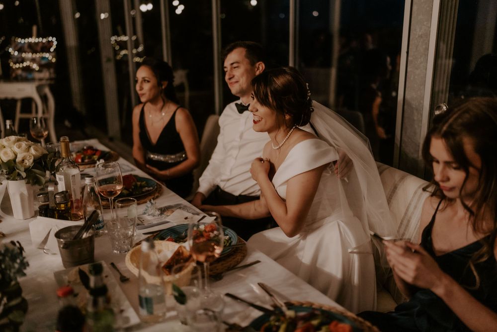 Wedding guests seated at tables watch the couple's first dance in an industrial reception space.