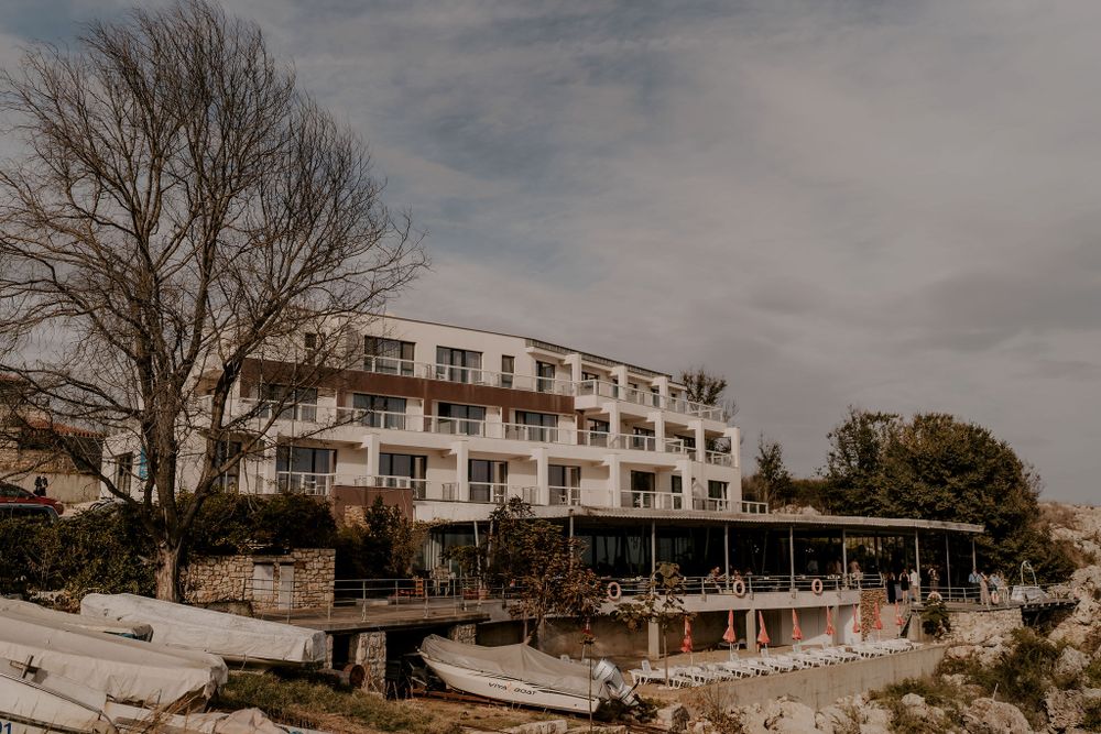 Panoramic view of a seaside hotel complex with bare trees under cloudy winter skies.