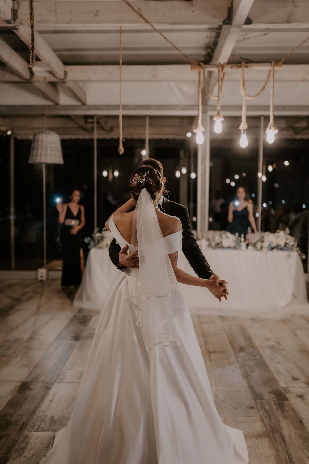 A flowing white wedding dress twirls during a dance in an industrial reception space.
