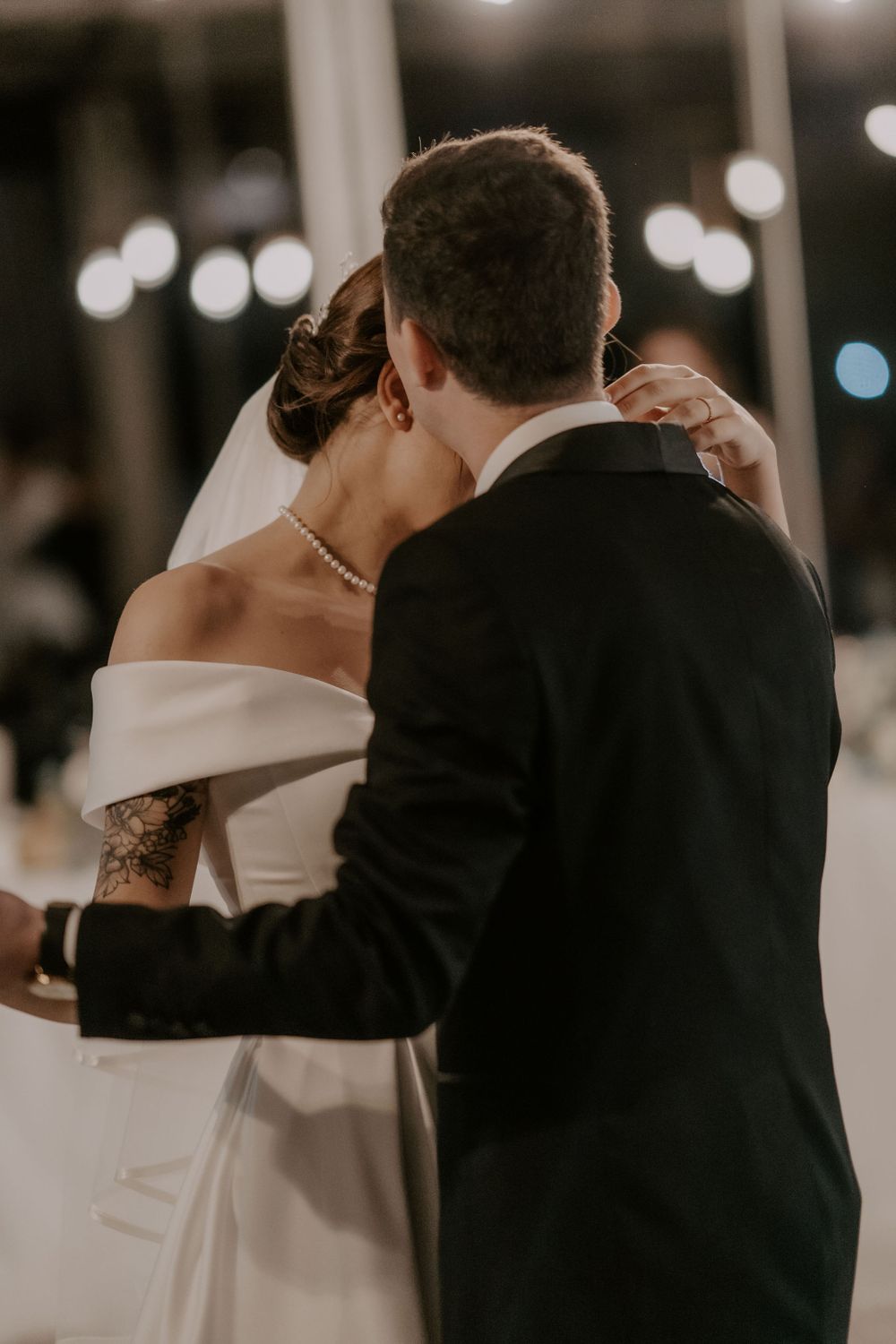 A romantic moment between newlyweds sharing their first dance, with soft bokeh lights in the background.