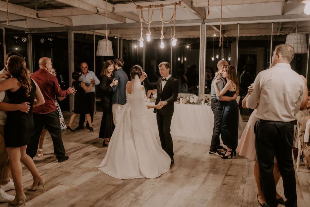 Wedding reception dance floor with couples dancing under hanging lights.