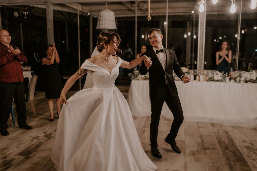 Energetic dance moves at a wedding reception with guests watching in the background.