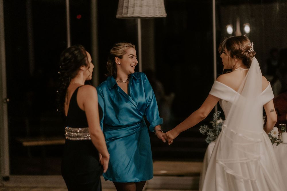 Wedding guests dancing and celebrating on a dimly lit dance floor at an evening reception.
