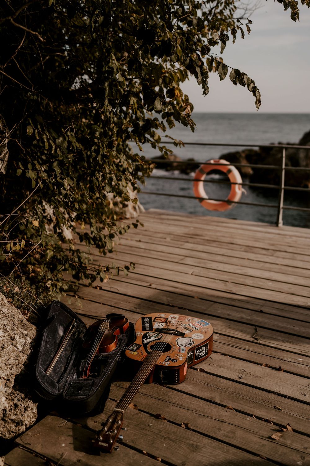Musical instruments and equipment on a wooden deck overlooking the water.