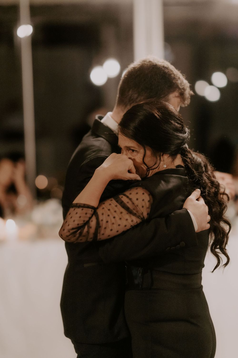 Guests embracing during an emotional moment at a wedding reception.