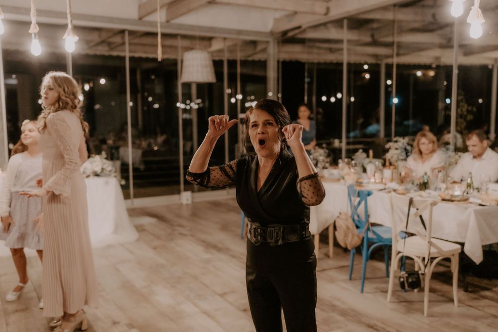 A guest in black attire speaks into a microphone during a wedding reception.