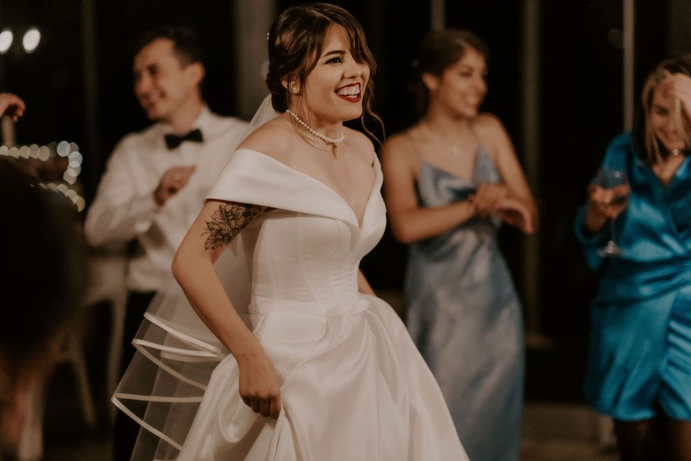 A bride in a stunning white off-shoulder gown dances during her wedding reception.