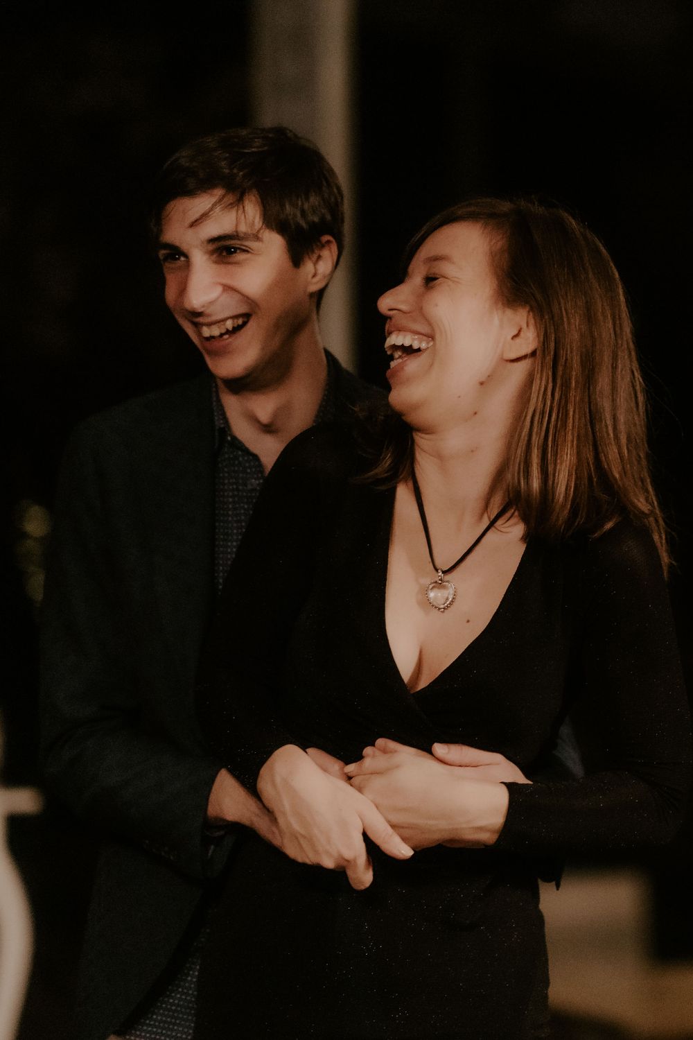 Guests share a candid moment of laughter during an evening wedding celebration.