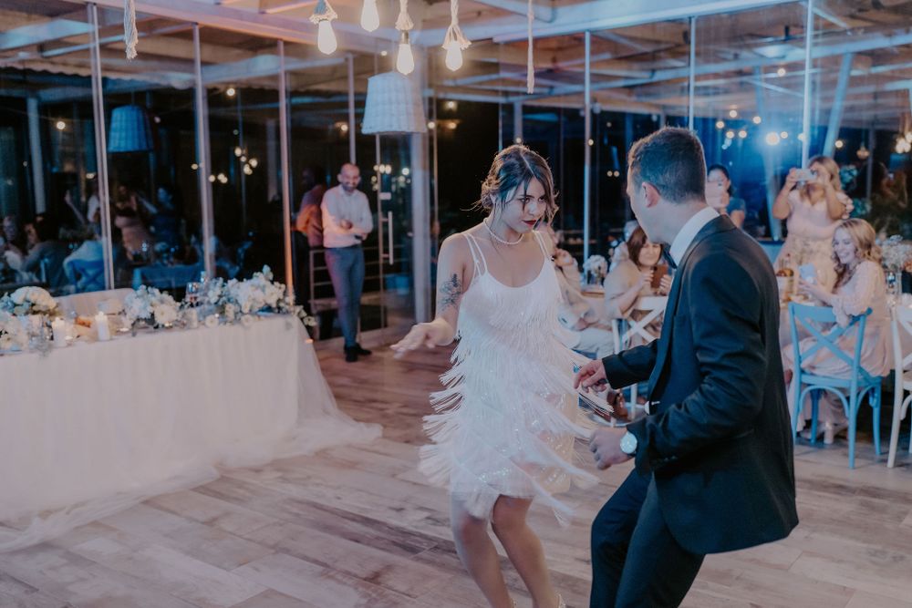 Wedding reception dance floor filled with guests celebrating under blue lighting.