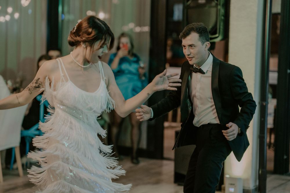 Elegant indoor wedding reception with guests mingling and dancing.