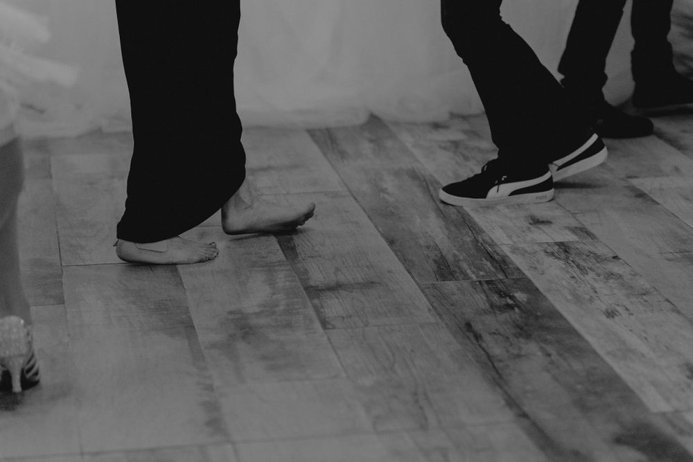 Close-up of dancing feet on wooden floor during wedding celebration.