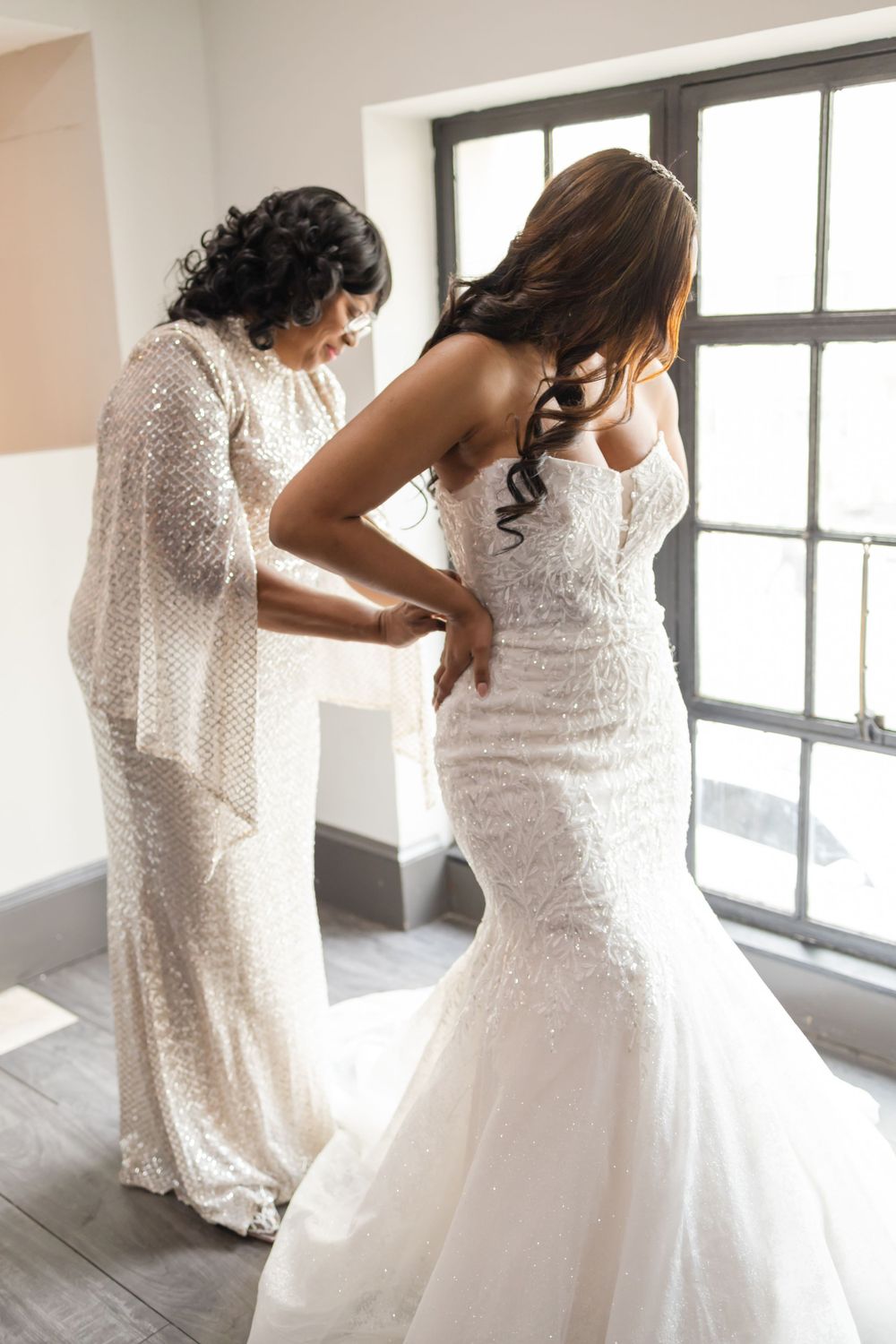 Final wedding dress fitting with mermaid style gown in bright room.