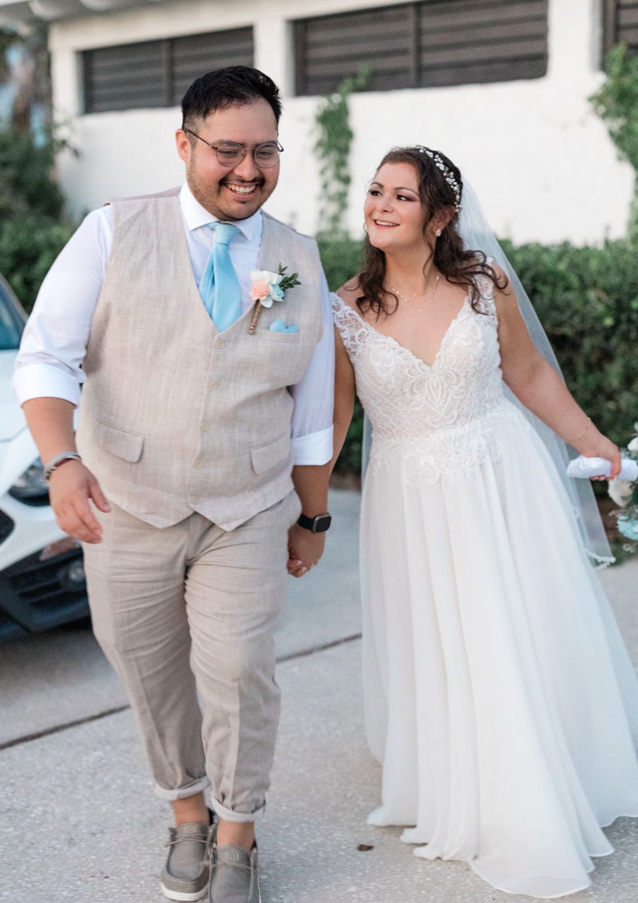 Wedding couple laughing and walking together in casual beach attire.