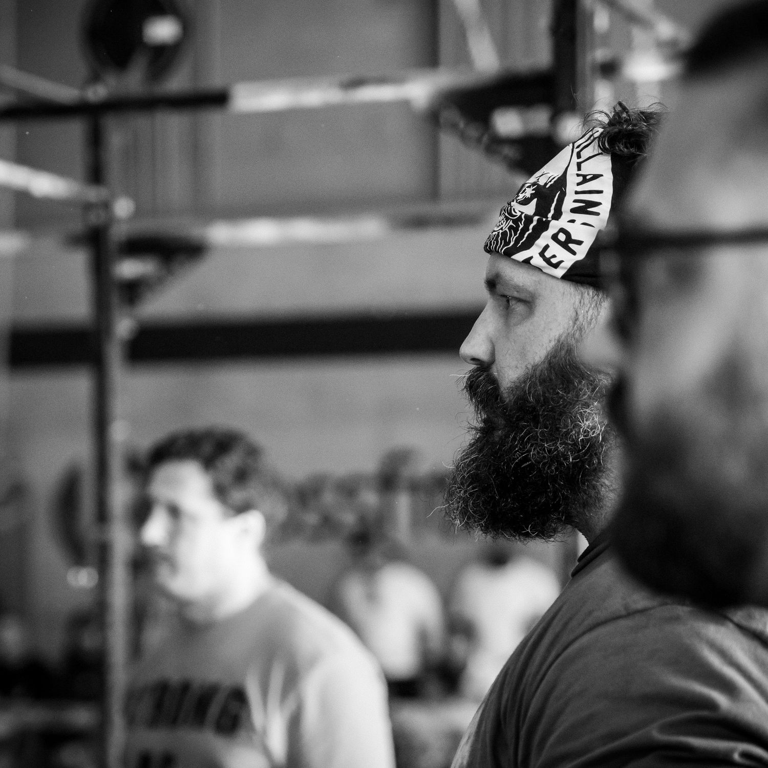 Black and white gym photo showing someone with a long beard wearing a headband during a workout.