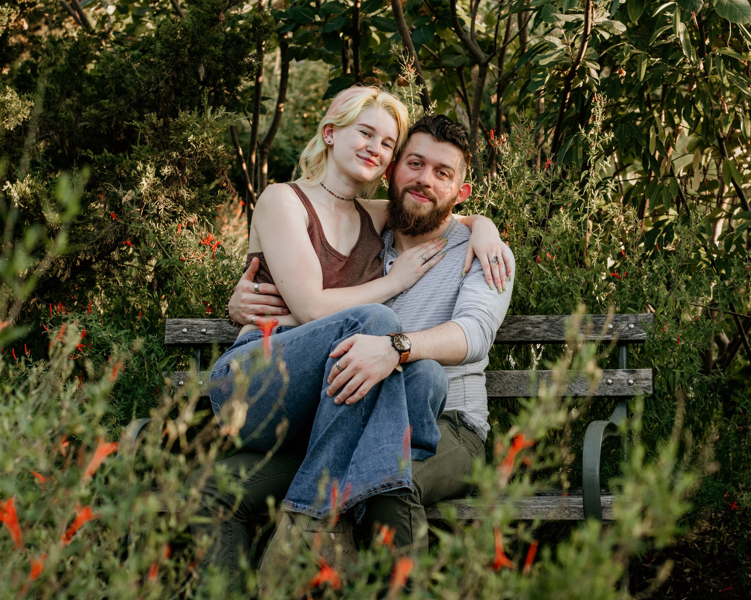 A couples photo taken behind some greenery