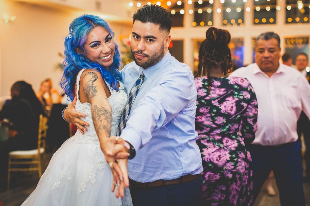 Wedding couple dancing together at their reception with blue-haired bride in white dress.