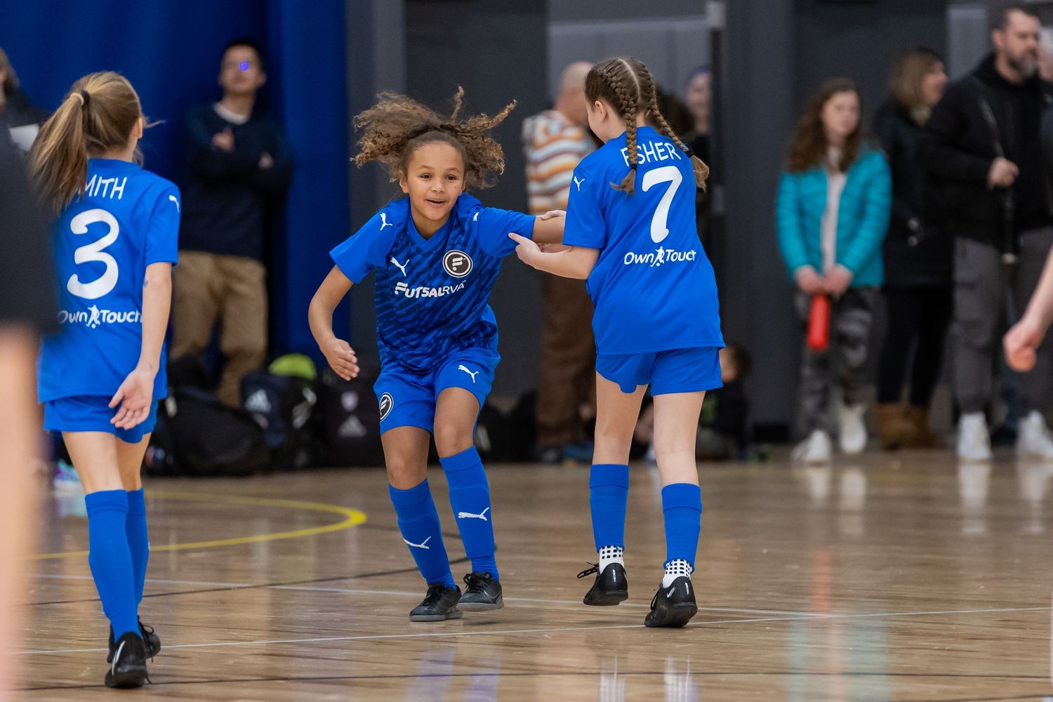 Athletes in bright blue uniforms gather on an indoor court during a sports match.
